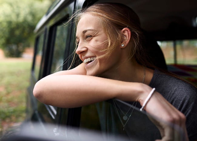 girl leaning out the window of a car