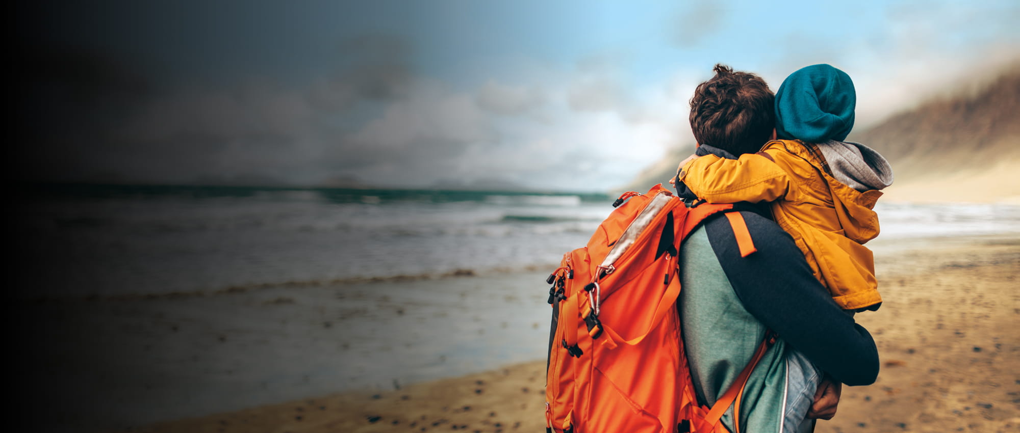A parent and a child embracing on the beach.