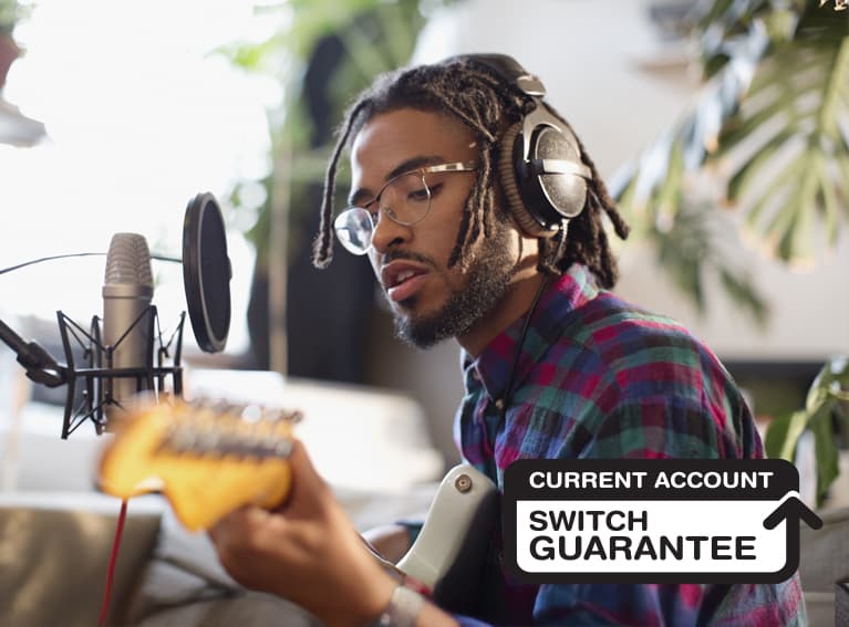 A man wearing headphones playing guitar.