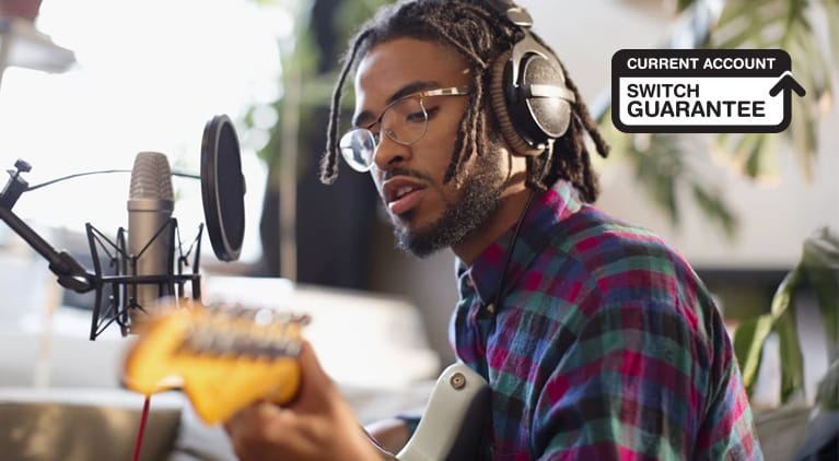 A man wearing headphones playing guitar.