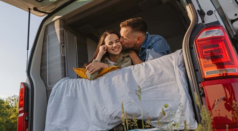 Couple looking out the back of a van.
