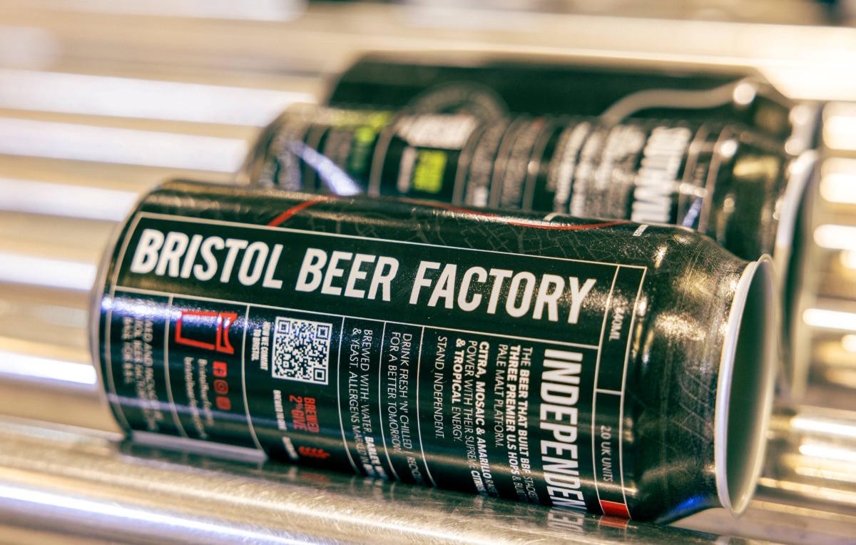 Close-up of a Bristol Beer Factory can lying on a production line conveyor, with branding and label details in sharp focus.