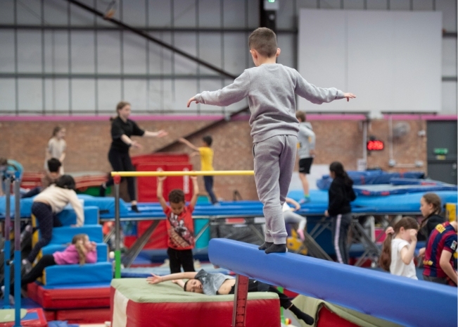 Young boy balancing on a beam in a gym.