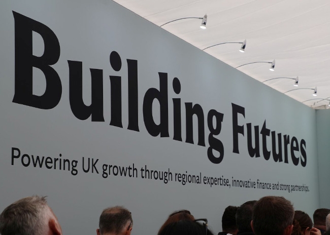 Interior view of the Lloyds Building Futures pavilion showcasing the event branding and audience at UKREiiF 2026.