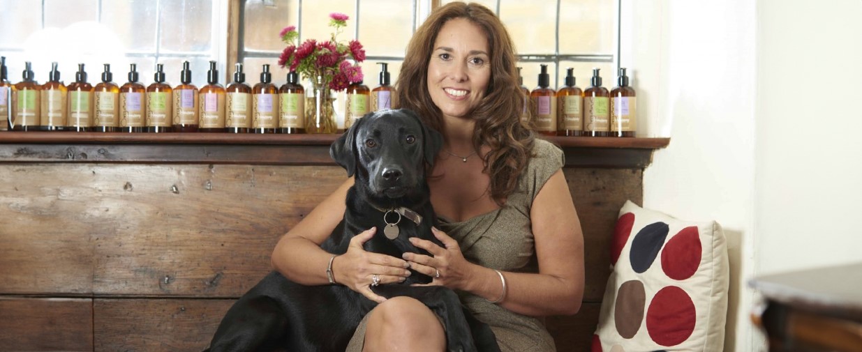 Emma Heathcote-James, Founder of Little Soap Company sat beside her dog and product line.