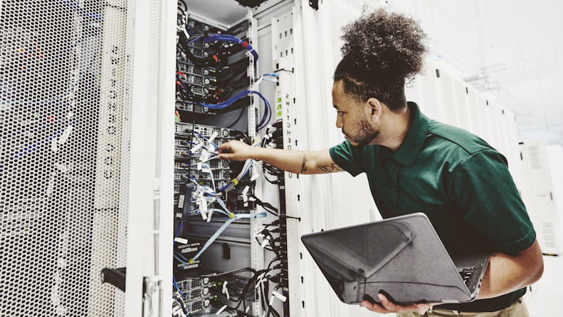 A male network engineer inspecting a rack of servers