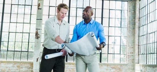 Two workers on building site looking at building plans