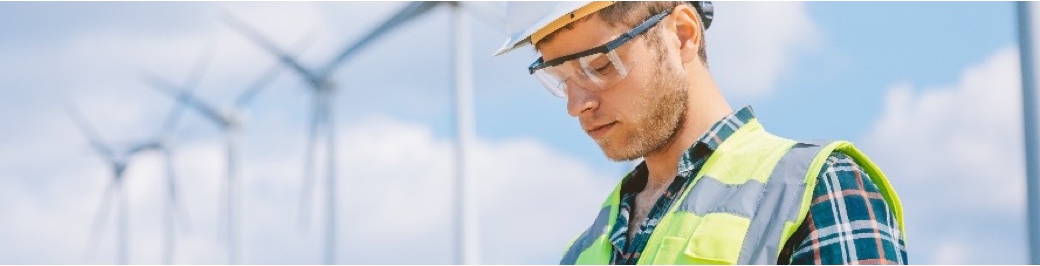 Man in high visibility with wind turbines in background
