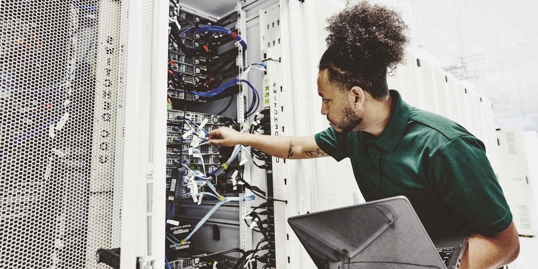 A male network engineer inspecting a rack of servers