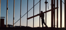 A construction worker carrying materials across a building site.