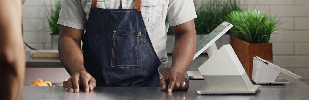Shopkeeper serving a customer using a Clover Station Pro countertop card machine