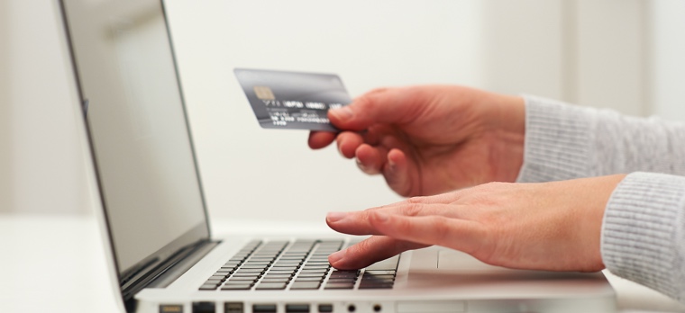 Image of a customer using a card to buy online using a laptop.