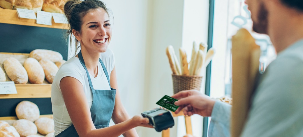 Customer completing a payment using a portable card machine in a bakery