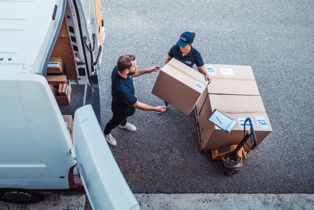 Two workers loading boxes into a van