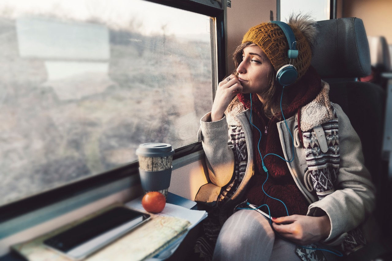 Person sat on a train with headphones on looking out of the window