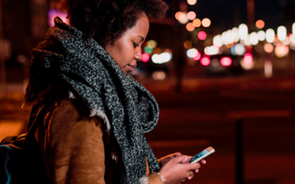 Younger woman outside at night looking at her phone screen