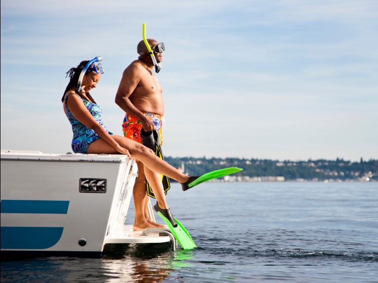 A retired couple, snorkelling from the back of a boat.
