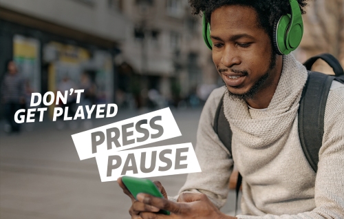 A young man with green headphones using his phone.