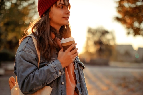 A smiling young woman holding a coffee cup.