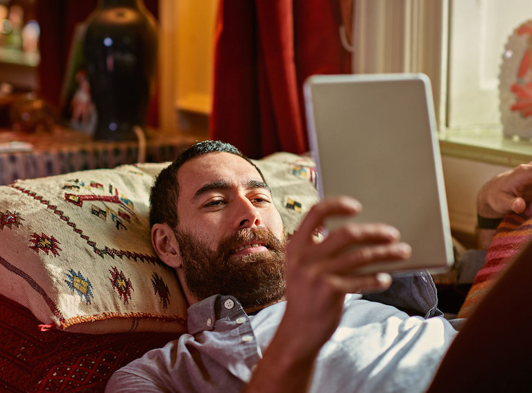 Man on sofa reading a tablet