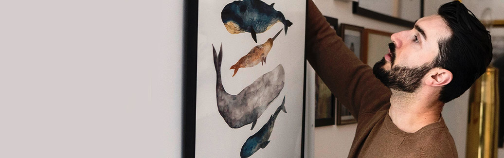Person hanging a painting of whales on the wall