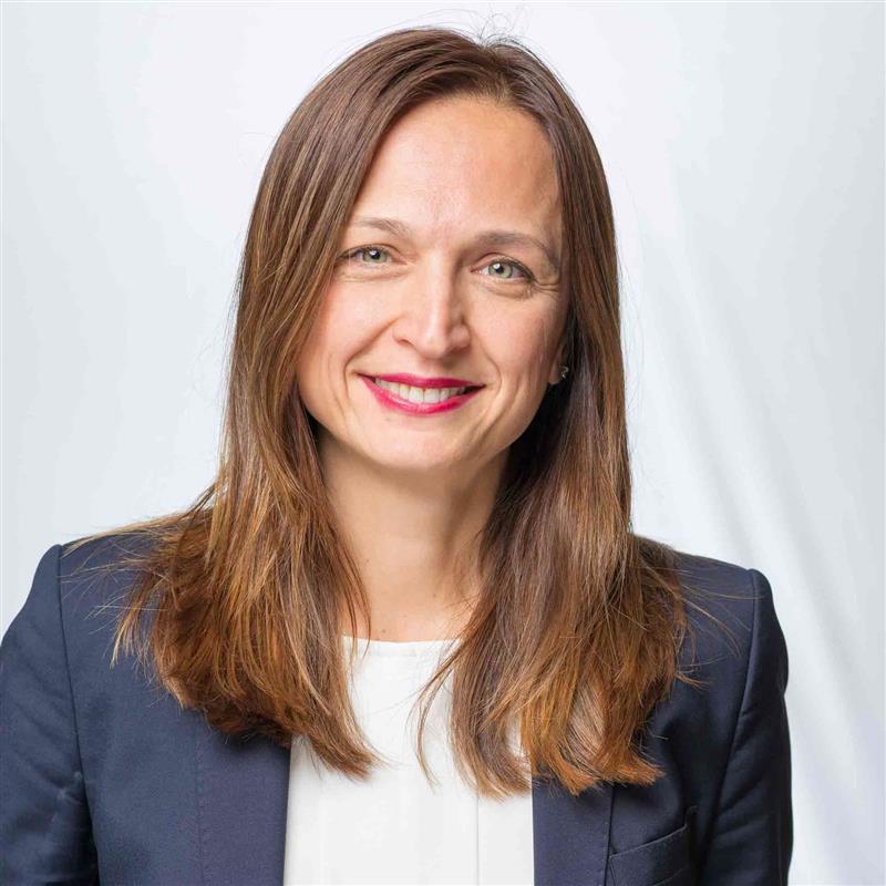 Head shot of smiling Ozlem Gunduz Robinson wearing a dark blue suit and white top.