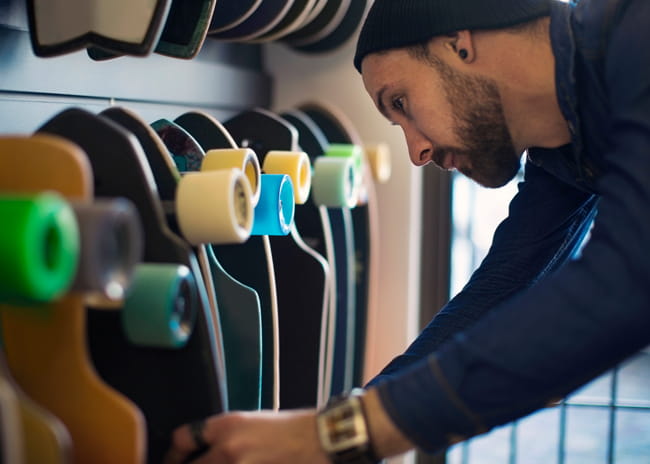 Man in shop looking at skateboards.