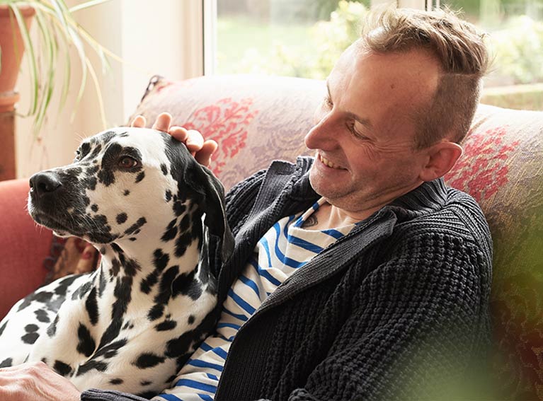 Man with dalmatian dog sitting on settee.