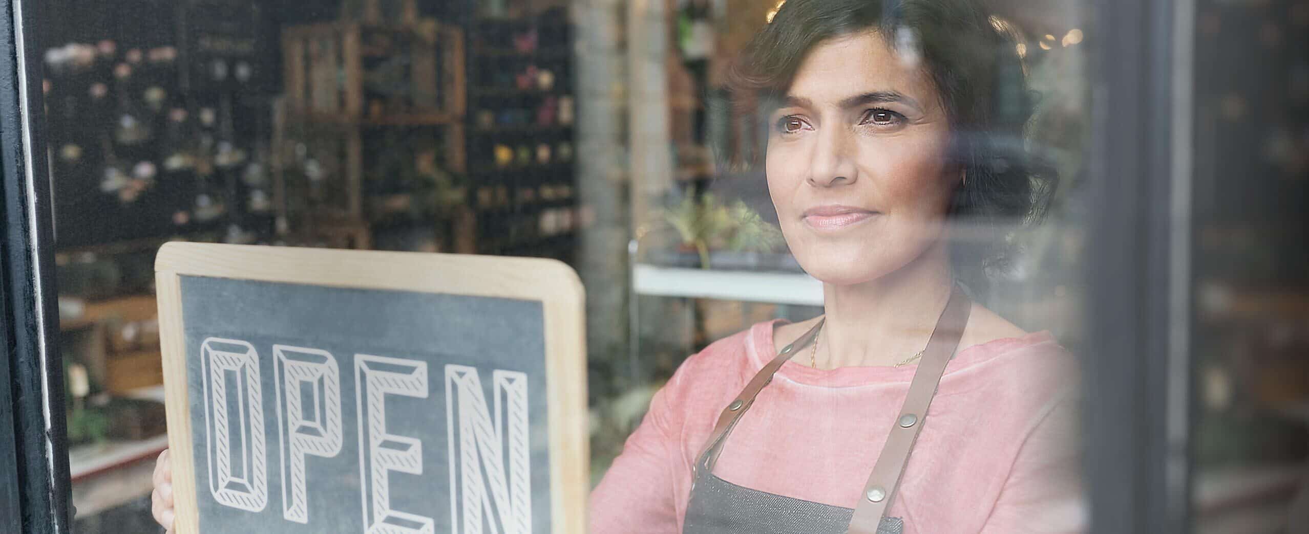 Woman turning an open sign on a glass door