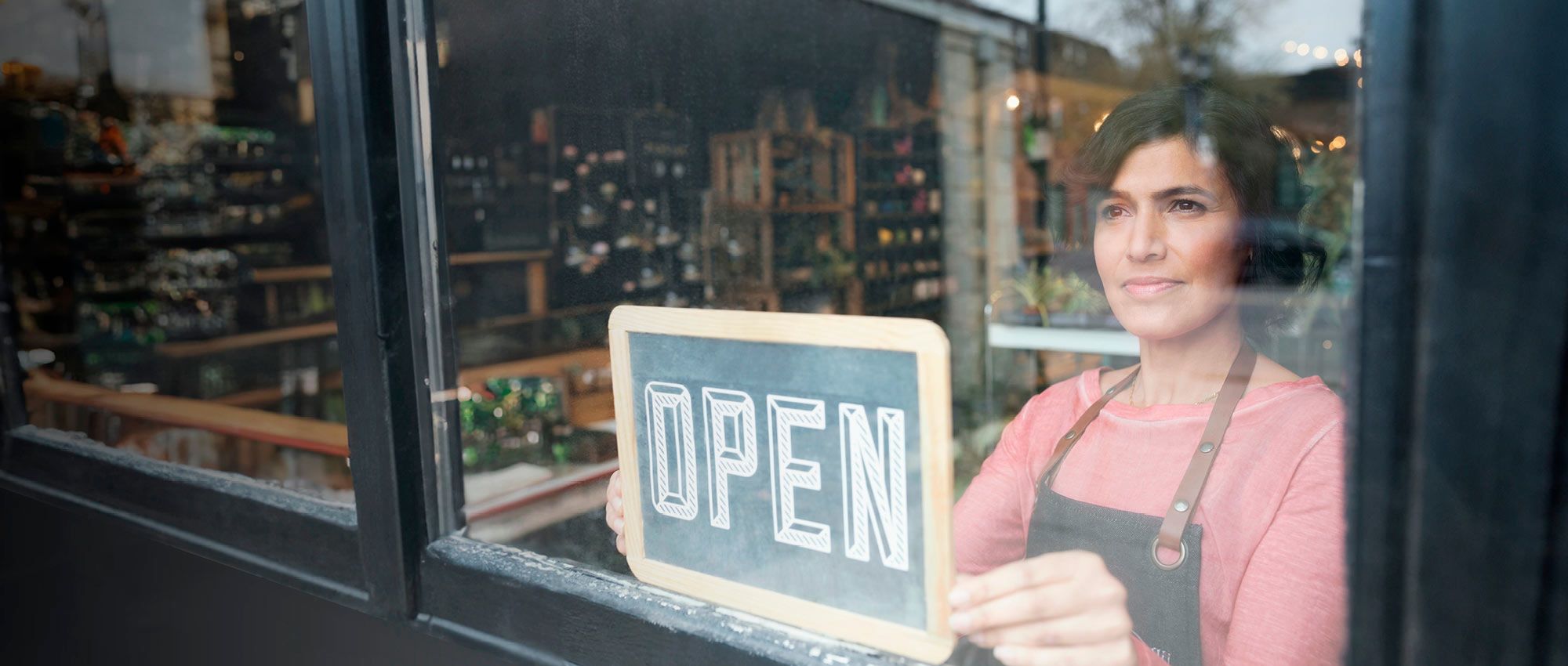Woman turning an open sign on a glass door