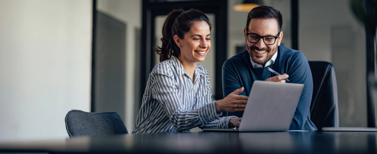 Man and woman looking at laptop device at an office desk