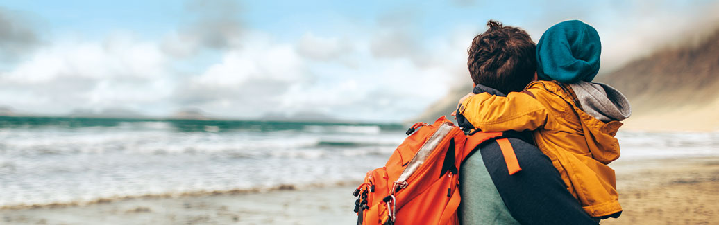 A parent and a child embracing on the beach.