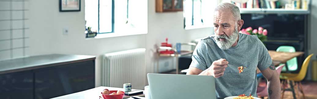 Man eating dinner whilst browsing the internet.