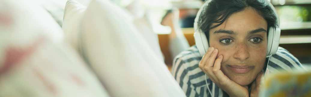 Header image of a girl listening to music with headphones in.