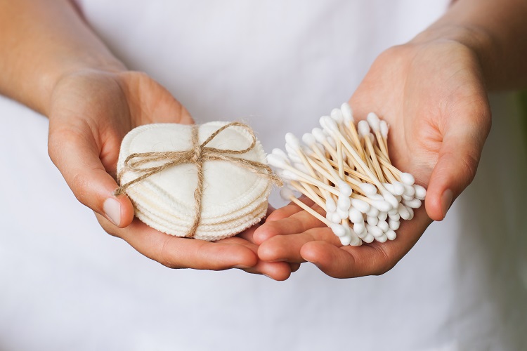 A person holding some cotton pads and buds