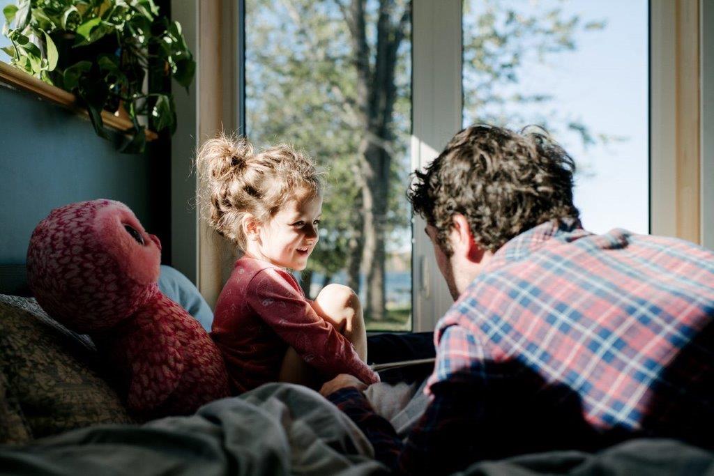 A man and smiling child in a bedroom.