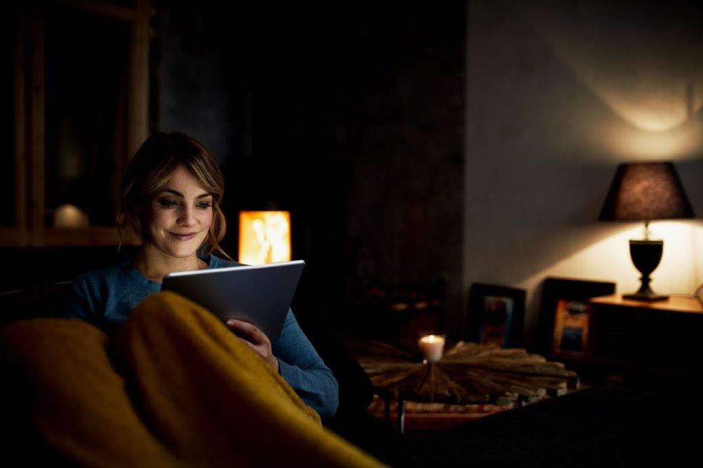 Young woman sitting on a sofa looking at a tablet.