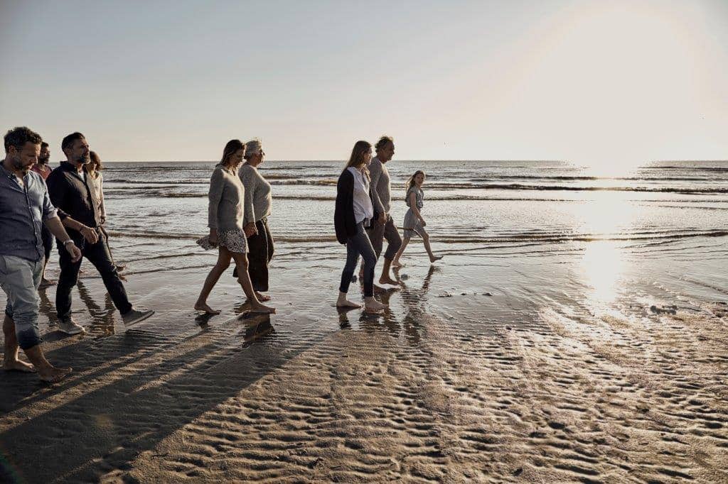 People walking on a beach as the sunsets