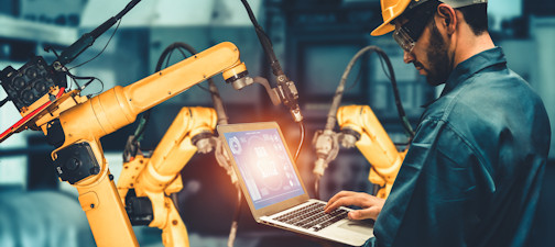 a man at a laptop and a robotic arm