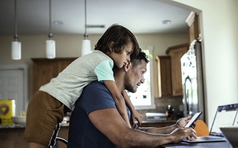 An image of a man with his child looking at his phone.
