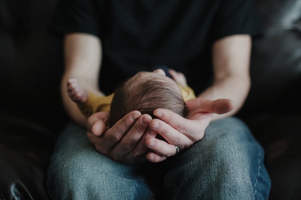 An image of hands holding a small baby.